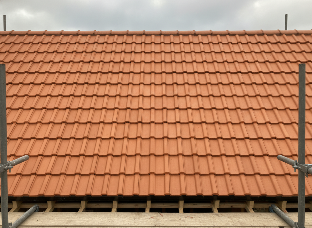 Newly laid terracotta clay tile roof on a British house with scaffolding in place