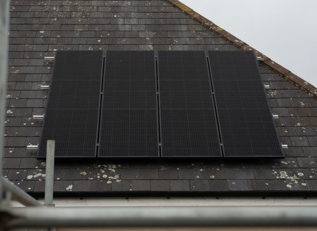 Black solar panels mounted on a weathered grey slate roof of a British house